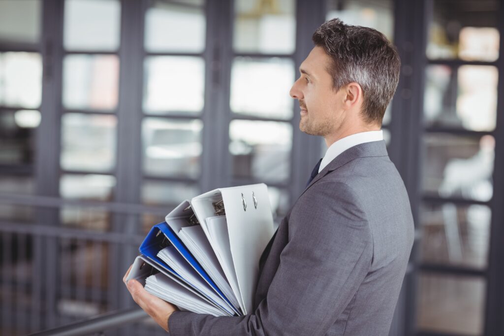 Imagem de um advogado empresarial-trabalhista segurando documentos em um escritório.