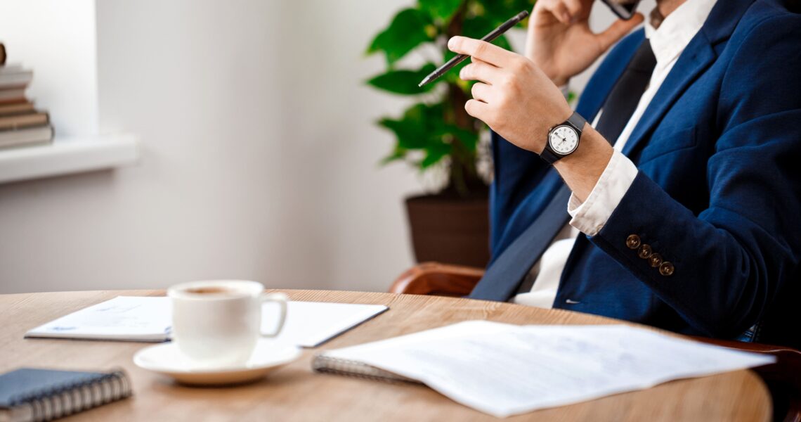 Advogado empresarial ao telefone com documentos sobre a mesa em ambiente corporativo