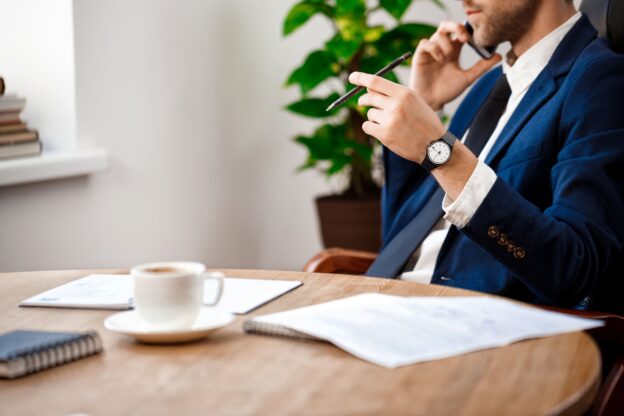 Advogado empresarial ao telefone com documentos sobre a mesa em ambiente corporativo
