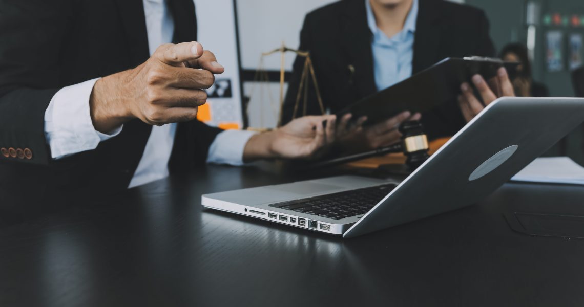 Advogados analisando documentos em notebook durante reunião estratégica sobre arbitragem empresarial como alternativa ao Judiciário.
