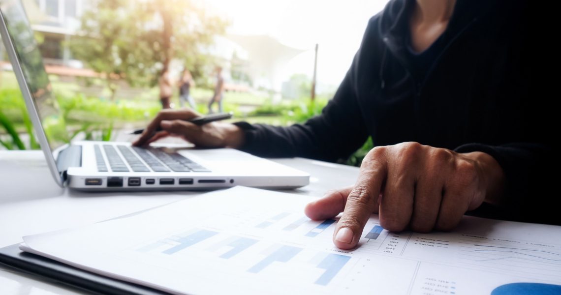 Profissional analisando relatórios financeiros em notebook, representando o planejamento tributário e os impactos da nova legislação tributária nas pequenas e médias empresas.