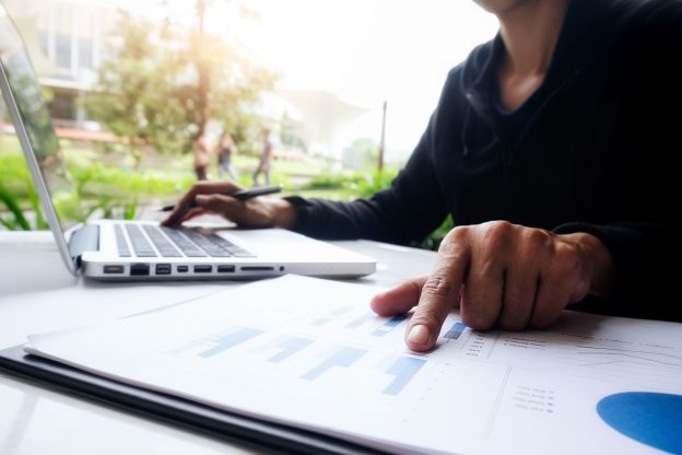 Profissional analisando relatórios financeiros em notebook, representando o planejamento tributário e os impactos da nova legislação tributária nas pequenas e médias empresas.