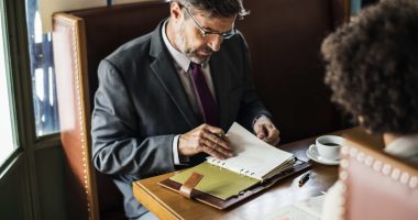 Advogado analisando contratos empresariais durante reunião com cliente para revisão de documentos