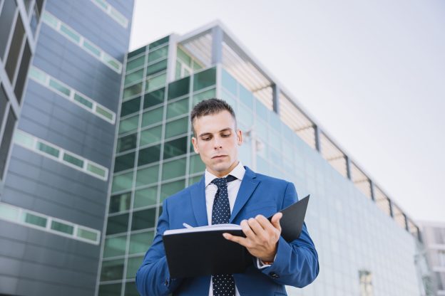 Advogado direito administrativo analisando documentos empresariais em frente a prédio corporativo moderno