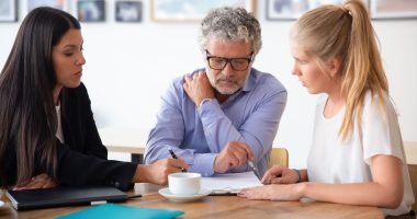 Família reunida com consultora em mesa de atendimento, analisando documentos sobre holding familiar.