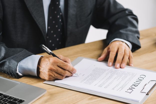 Pessoa assinando contrato em mesa de trabalho, representando riscos jurídicos em contratos copiados da internet.