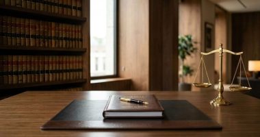 Mesa de escritório de advocacia com balança da justiça, livros jurídicos e pasta de planejamento sobre os impactos da reforma tributária.
